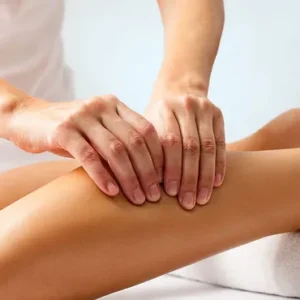 Sports massage therapist applying pressure to a patient's leg